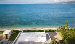 Modern seaside residence featuring concrete and glass materials with beautiful ocean views.