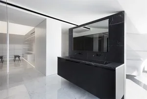 Modern, minimalist bathroom featuring black marble sink and white marble flooring.