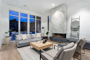A modern living room with a marble fireplace and wooden furniture.