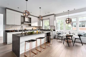 A modern residential kitchen with black countertops and white cabinets.