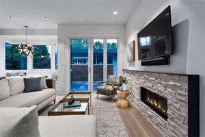 A modern living room featuring wooden textured furniture and concrete surfaces, with a stone fireplace and a flat-screen TV m