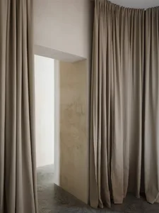 A minimalist interior space featuring beige curtains.