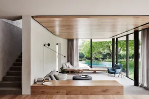 Modern residential living room with a pool view, featuring wood and concrete materials, and a comfortable seating area.