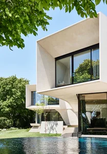 Modern house with concrete exterior featuring large glass windows and a swimming pool.