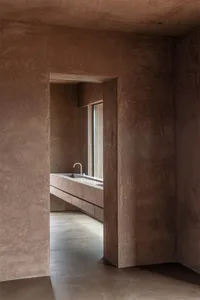 Modern bathroom with concrete walls and floor, featuring a minimalist sink and natural light from a large window.