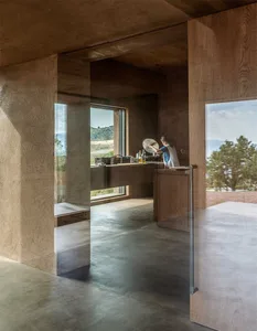 A modern kitchen with concrete walls and flooring, featuring a minimalist design.