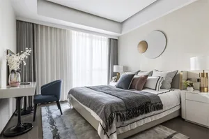 A modern bedroom featuring a brown couch, white flowers, and white curtains.