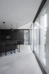 Modern, minimalist kitchen with concrete flooring and black furniture.