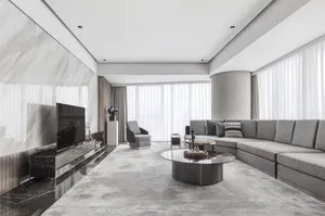 A modern minimalist living room featuring a gray sectional sofa, a round glass coffee table with marble accents, and a marble