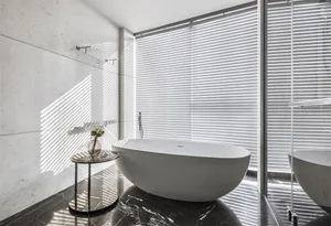 Modern minimalist bathroom featuring a freestanding bathtub, marble floor, and glass enclosure.