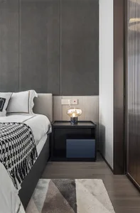 A minimalist bedroom with a bed, nightstand, and lamp, featuring gray fabric, glass, and metal materials.