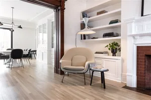 Minimalist modern living room with white furniture and wooden floors.