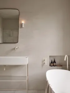 A minimalist modern bathroom with concrete walls and floors, a white sink, and a freestanding bathtub.