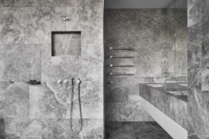 A modern bathroom with marble walls and a sink.