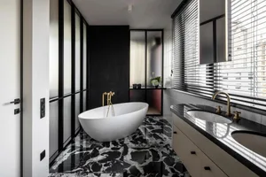 Modern bathroom with a freestanding bathtub and double sinks on a black marble floor.