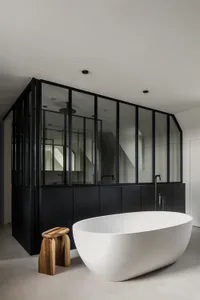 A minimalist bathroom with a smooth concrete floor and a white oval bathtub.