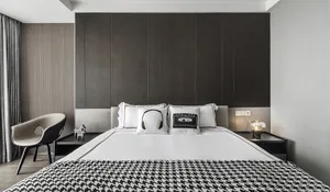 A modern bedroom with a black and white color scheme, featuring a bed with a black and white checkered blanket and decorative
