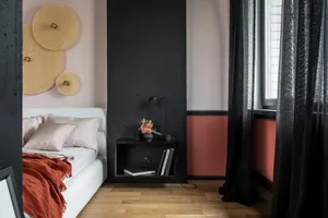 A modern bedroom with a concrete wall, a blackboard, and pink accents.