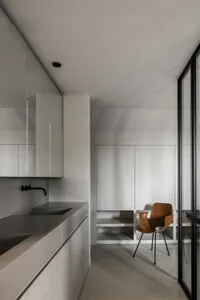 A modern bathroom with minimalist design, featuring concrete countertops and a single faucet.