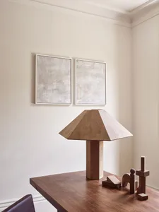A modern table lamp made of concrete with a geometric design, placed on a wooden table in a minimalist setting.