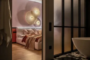 A modern bedroom featuring textured wall lights, a cozy bed, and a clean, minimalistic design.