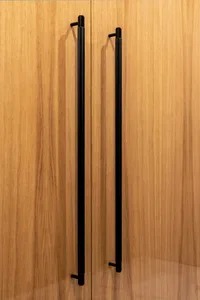 A modern interior design featuring a wooden door with a black handle.
