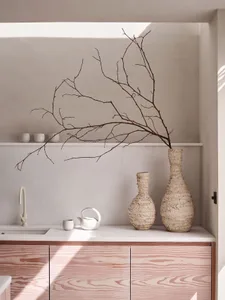 Modern kitchen with scallop-patterned cabinets and organic vases.