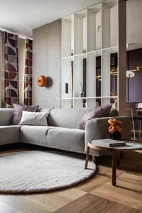 A modern living room with concrete walls, large windows, and a comfortable sofa.