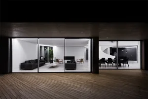 Modern living room with concrete walls and floor, featuring a cozy seating area and a minimalist design.