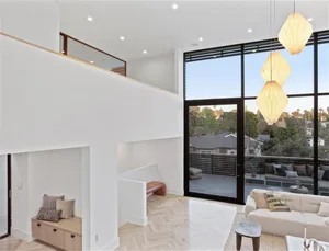 Modern living room with concrete walls, wooden flooring, and large windows.