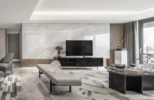 A modern living room with a marble accent wall, black furniture, and a light-colored bench in front of a television.