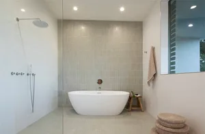 A modern minimalist bathroom with a freestanding bathtub, a walk-in shower, and ceramic tiles on the walls and floor.