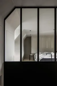 一間擁有混凝土牆面與玻璃窗的現代極簡臥室。