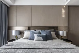 Modern minimalist bedroom with fabric bedding and wooden furniture.
