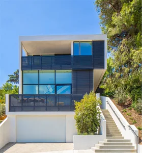 Modern house with metal and glass exterior and stairs leading up to it.