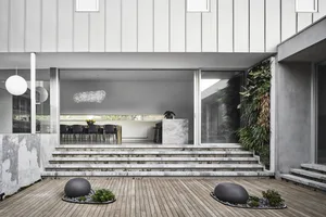 Modern residential interior featuring a concrete courtyard with steps and a wooden deck.