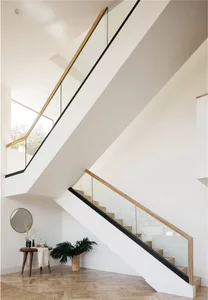 Modern staircase design featuring concrete steps, glass balustrades, and wooden railings.