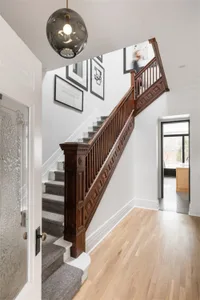 Modern stairwell with wooden railings and carpeted steps, featuring a spherical light fixture and framed artwork.