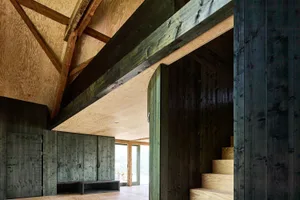 Modern wooden interior space with a floor plan view showing a living area with a large window, wooden walls, and a staircase.
