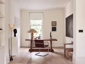 Minimalist home office featuring a wooden desk, leather chair, and various artworks.