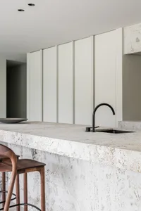 Modern, minimalist kitchen bar counter featuring a marble countertop and sleek black faucet.