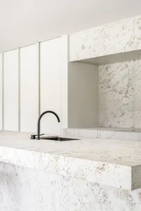 Modern minimalist kitchen featuring white marble countertops and backsplash.
