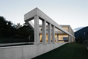 Modern residential house exterior with concrete structure and large windows.