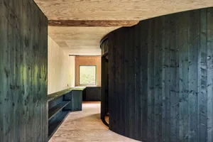 A photograph of a modern industrial wooden room with curved walls and a window.