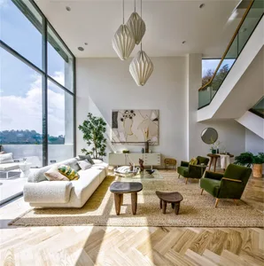 A contemporary living room featuring white and green furniture, a woven rug, and geometric light fixtures.