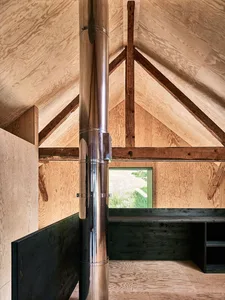 Modern minimalist interior with exposed wooden beams and a metal chimney.