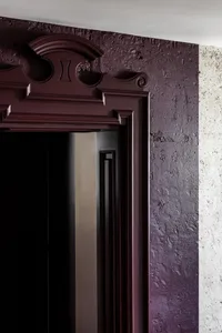 Dark purple door detail with ornate trim and marble textured wall