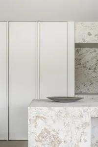 A modern minimalist kitchen with marble countertops and sleek, white cabinetry.