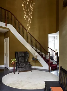 Modern staircase entry with hardwood floors, dark wood railings, and a hanging chandelier.