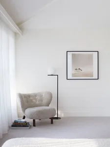 A minimalist white interior featuring a textured upholstered chair.